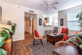 A living room with a black and white rug, a brown couch, and a ceiling fan.